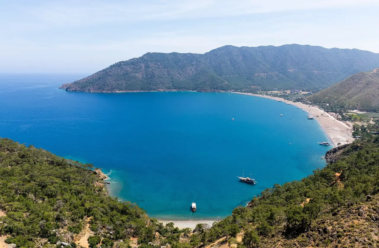 Adrasan bay from above, a sheltered curve of beach between pine-covered mountains
