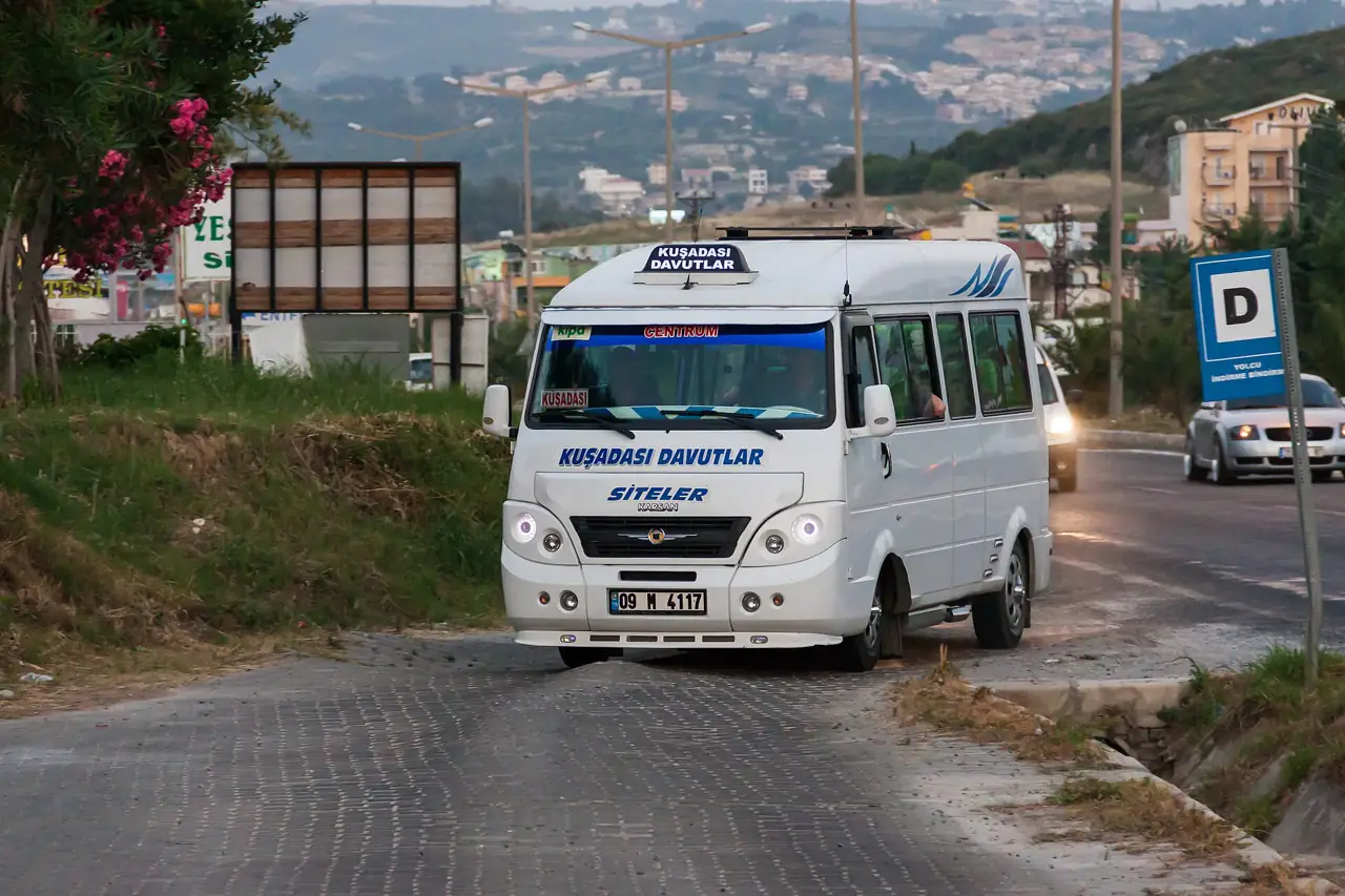 A white dolmuş minibus on a coastal road