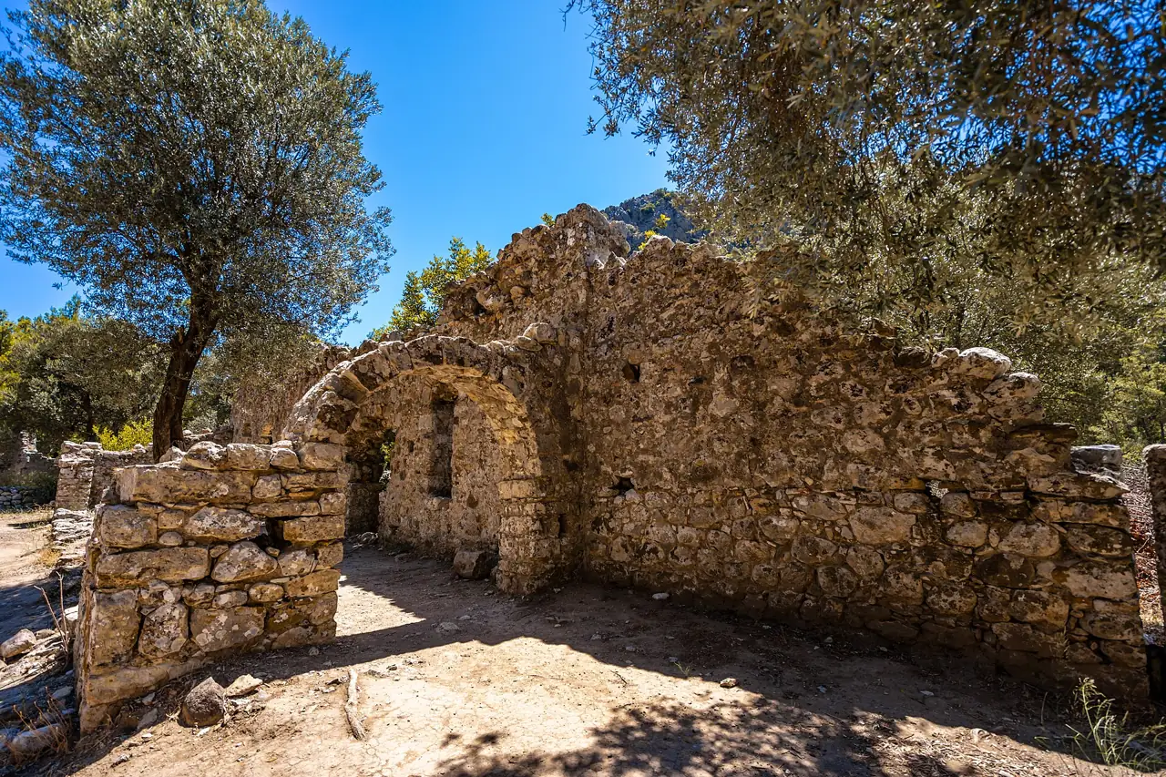 Stone ruins of ancient Olympos among trees in the river valley